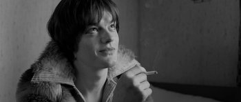 Movie still from “Control” (2007), directed by Anton Corbijn – A young man holding a cigarette in his mouth; Close Up shot, High angle