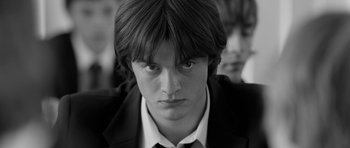 Movie still from “Control” (2007), directed by Anton Corbijn – A young man in a suit and tie looking at the camera; Close Up shot, Low angle