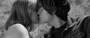 Movie still from “Control” (2007), directed by Anton Corbijn – A young man and a young woman kissing in a field; Close Up shot, High angle