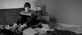 Movie still from “Control” (2007), directed by Anton Corbijn – A young man sitting on the floor in front of a computer; Medium shot, Overhead angle