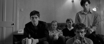 Movie still from “Control” (2007), directed by Anton Corbijn – A group of young men sitting on top of a couch; Medium shot, Low angle