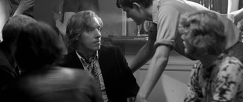 Movie still from “Control” (2007), directed by Anton Corbijn – A man in a suit and tie looking at another man in a tie; Medium shot, Over the shoulder angle