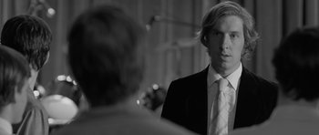 Movie still from “Control” (2007), directed by Anton Corbijn – A black and white photo of a man in a suit and tie; Close Up shot, Over the shoulder angle