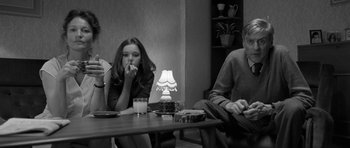 Movie still from “Control” (2007), directed by Anton Corbijn – Two people are sitting at a table eating food; Medium shot, Over the shoulder angle