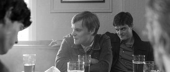 Movie still from “Control” (2007), directed by Anton Corbijn – A man sitting at a table with a glass of water in front of him; Close Up shot, Low angle