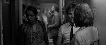 Movie still from “Control” (2007), directed by Anton Corbijn – A man and a woman standing next to each other in a room; Medium shot, Over the shoulder angle