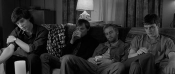 Movie still from “Control” (2007), directed by Anton Corbijn – A couple of men sitting on top of a couch; Medium shot, High angle