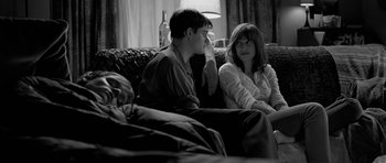 Movie still from “Control” (2007), directed by Anton Corbijn – A man and a woman sitting on a couch next to each other; Medium shot, Over the shoulder angle