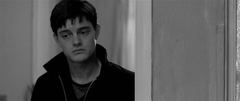 Movie still from “Control” (2007), directed by Anton Corbijn – Black and white photograph of a young man looking at the camera; Close Up shot, Over the shoulder angle