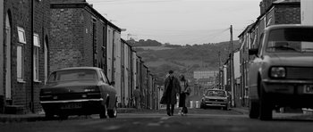 Movie still from “Control” (2007), directed by Anton Corbijn – A man and a woman walking down a street; Wide shot, High angle