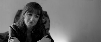 Movie still from “Control” (2007), directed by Anton Corbijn – Black and white photograph of a woman leaning against a wall; Close Up shot, Over the shoulder angle