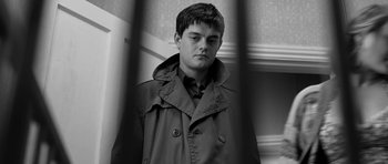 Movie still from “Control” (2007), directed by Anton Corbijn – Black and white photograph of a young man in a trench coat; Close Up shot, Low angle