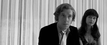 Movie still from “Control” (2007), directed by Anton Corbijn – Black and white photograph of a man wearing a suit and tie; Close Up shot, Low angle