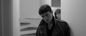 Movie still from “Control” (2007), directed by Anton Corbijn – A man and a woman standing next to each other in front of a staircase; Close Up shot, Over the shoulder angle