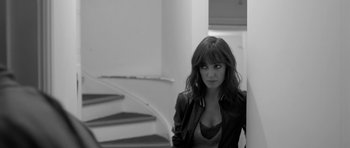 Movie still from “Control” (2007), directed by Anton Corbijn – A black and white photo of a woman standing in front of a staircase; Medium shot, High angle