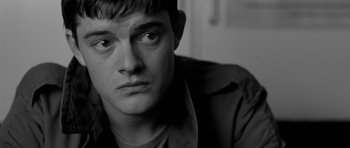 Movie still from “Control” (2007), directed by Anton Corbijn – Black and white photograph of a young man looking into the distance; Close Up shot, Over the shoulder angle