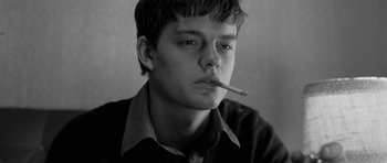 Movie still from “Control” (2007), directed by Anton Corbijn – A young man smoking a cigarette in a black and white photo; Close Up shot, Low angle