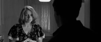 Movie still from “Control” (2007), directed by Anton Corbijn – A woman in a black and white photo looking into a mirror; Medium shot, Over the shoulder angle