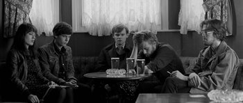 Movie still from “Control” (2007), directed by Anton Corbijn – Two men sitting at a table in front of a window; Medium shot, High angle