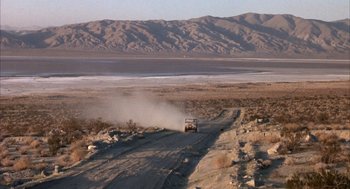 Movie still from “Coogan's Bluff” (1968), directed by Don Siegel – A truck driving down a dirt road in the middle of the desert; Extreme Wide shot, High angle