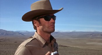 Movie still from “Coogan's Bluff” (1968), directed by Don Siegel – A man wearing a cowboy hat and holding a gun; Medium shot, Low angle