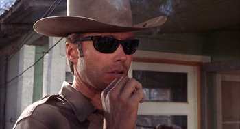 Movie still from “Coogan's Bluff” (1968), directed by Don Siegel – A man in a hat and sunglasses smoking a cigarette; Close Up shot, Low angle