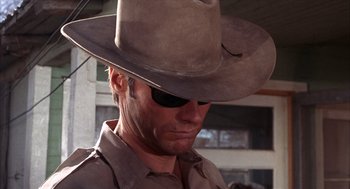 Movie still from “Coogan's Bluff” (1968), directed by Don Siegel – A man wearing a cowboy hat and a pair of sunglasses; Close Up shot, Low angle