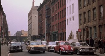 Movie still from “Coogan's Bluff” (1968), directed by Don Siegel – Cars parked on the side of the road near a building; Extreme Wide shot, High angle