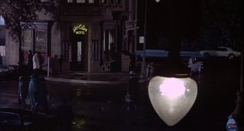 Movie still from “Coogan's Bluff” (1968), directed by Don Siegel – A night view of a city street with a heart shaped hotel sign; Wide shot, High angle