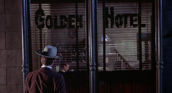 Movie still from “Coogan's Bluff” (1968), directed by Don Siegel – A man wearing a hat looking out of a window; Wide shot, Low angle