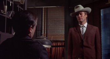 Movie still from “Coogan's Bluff” (1968), directed by Don Siegel – A man wearing a cowboy hat talking to another man in a suit; Medium shot, Over the shoulder angle