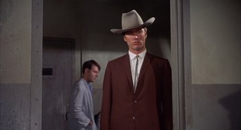 Movie still from “Coogan's Bluff” (1968), directed by Don Siegel – A man wearing a suit and a cowboy hat; Medium shot, Low angle