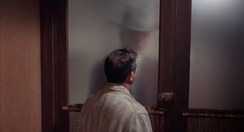 Movie still from “Coogan's Bluff” (1968), directed by Don Siegel – A man standing in front of an open door; Medium shot, Over the shoulder angle