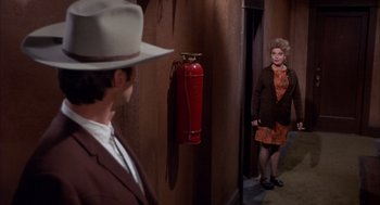 Movie still from “Coogan's Bluff” (1968), directed by Don Siegel – A man and a woman standing in front of a fire hydrant; Wide shot, High angle