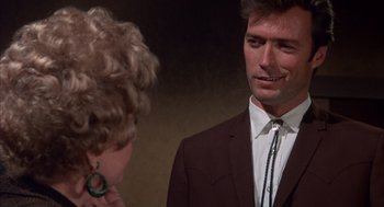Movie still from “Coogan's Bluff” (1968), directed by Don Siegel – A man in a suit and tie talking to a woman; Close Up shot, Over the shoulder angle
