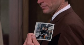 Movie still from “Coogan's Bluff” (1968), directed by Don Siegel – A man holding up a picture of a man and a woman on a motorcycle; Extreme Close Up shot, Over the shoulder angle