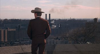 Movie still from “Coogan's Bluff” (1968), directed by Don Siegel – A man wearing a hat standing on top of a hill; Wide shot, Low angle