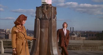 Movie still from “Coogan's Bluff” (1968), directed by Don Siegel – A man and a woman standing next to a statue; Wide shot, Low angle