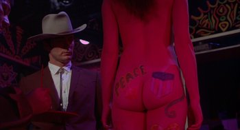 Movie still from “Coogan's Bluff” (1968), directed by Don Siegel – A man in a suit standing next to a woman in a pink bodysuit; Medium shot, Over the shoulder angle