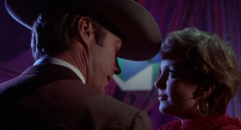 Movie still from “Coogan's Bluff” (1968), directed by Don Siegel – A man and a woman face to face in front of a purple curtain; Close Up shot, Low angle