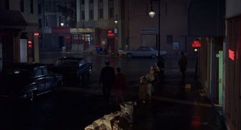 Movie still from “Coogan's Bluff” (1968), directed by Don Siegel – A couple of people walking down a street at night; Extreme Wide shot, High angle