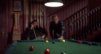 Movie still from “Coogan's Bluff” (1968), directed by Don Siegel – Two men are playing a game of billiards together; Medium shot, High angle