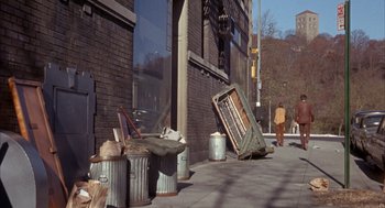 Movie still from “Coogan's Bluff” (1968), directed by Don Siegel – A street scene with trash on the sidewalk and trash cans; Wide shot, High angle