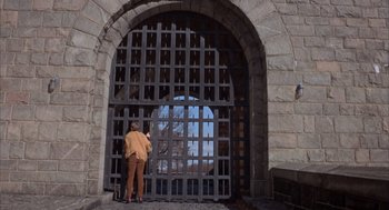 Movie still from “Coogan's Bluff” (1968), directed by Don Siegel – A person standing in front of a gate; Extreme Wide shot, High angle