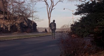 Movie still from “Coogan's Bluff” (1968), directed by Don Siegel – A man walking down the street holding a stick; Extreme Wide shot, High angle