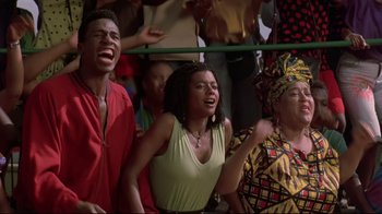 Movie still from “Cool Runnings” (1993), directed by Jon Turteltaub – A group of young people singing in a crowd of onlookers; Medium shot, Low angle
