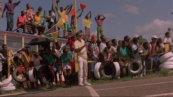 Movie still from “Cool Runnings” (1993), directed by Jon Turteltaub – A group of people standing in a parking lot; Extreme Wide shot, Low angle