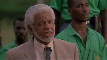 Movie still from “Cool Runnings” (1993), directed by Jon Turteltaub – An older man in a suit and tie; Close Up shot, Low angle