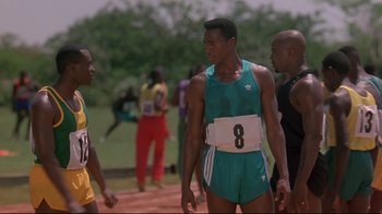 Movie still from “Cool Runnings” (1993), directed by Jon Turteltaub – A group of men standing next to each other on a track; Medium shot, Over the shoulder angle