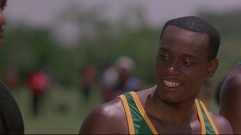 Movie still from “Cool Runnings” (1993), directed by Jon Turteltaub – A person with a green and yellow shirt; Close Up shot, Over the shoulder angle